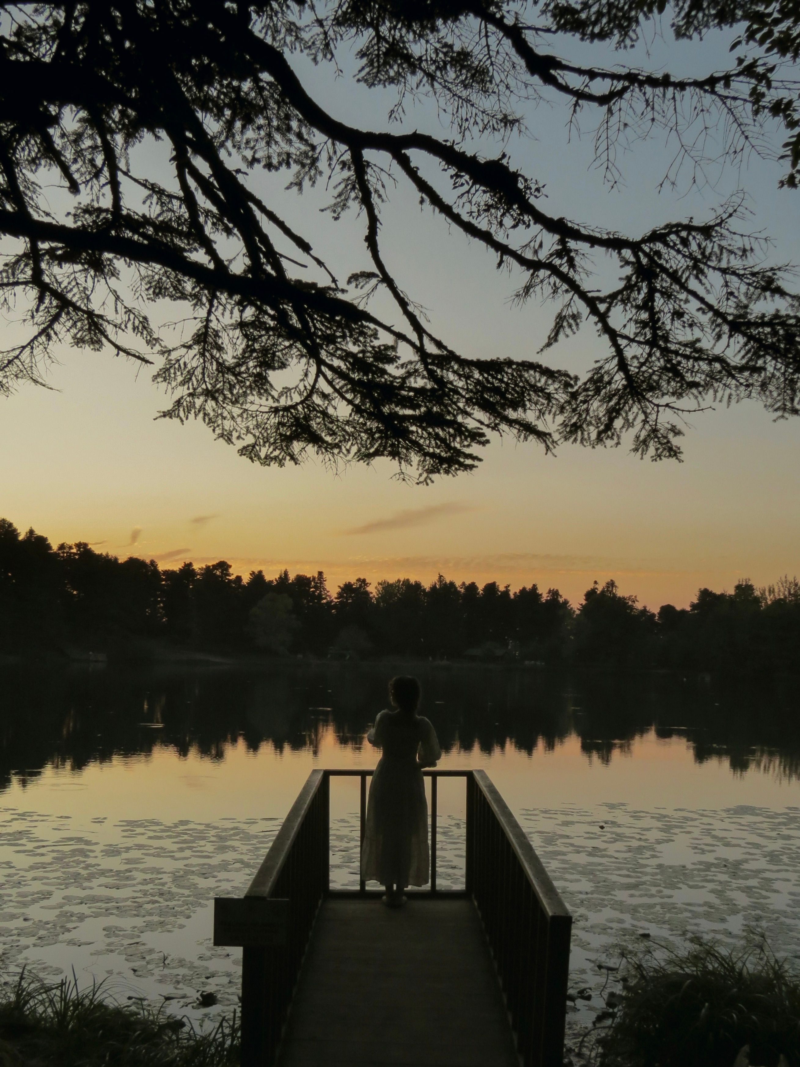Silhouette of Woman at Sunset on Lakeside Dock · Free Stock Photo