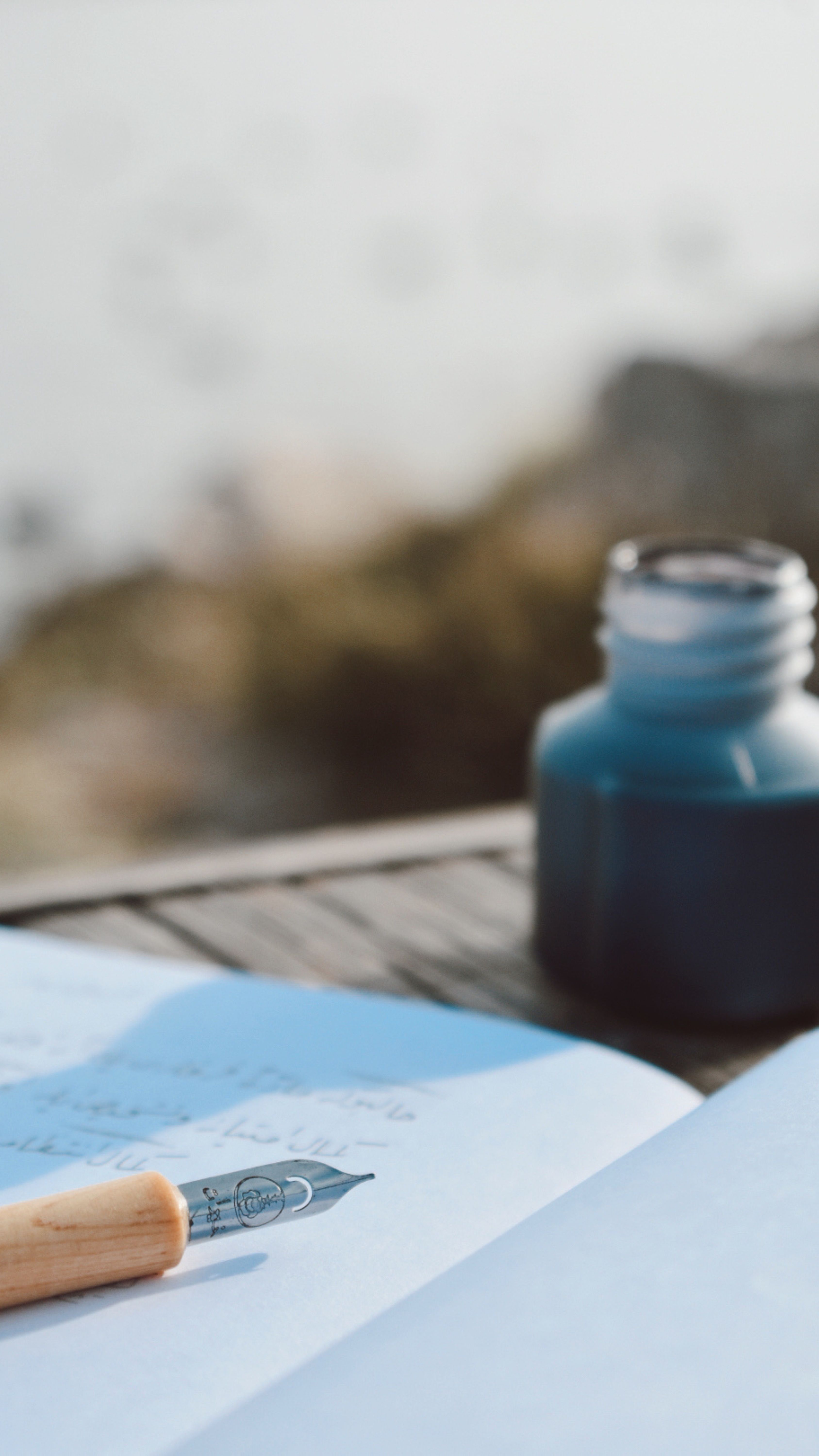 A handwritten notebook open beside a fountain pen on a desk