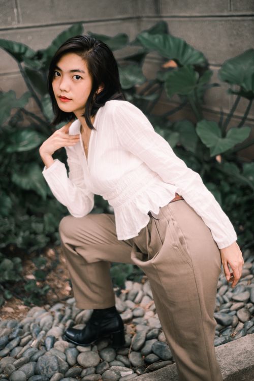 Free Fashionable Asian woman posing in a garden setting, showcasing elegance and style. Stock Photo