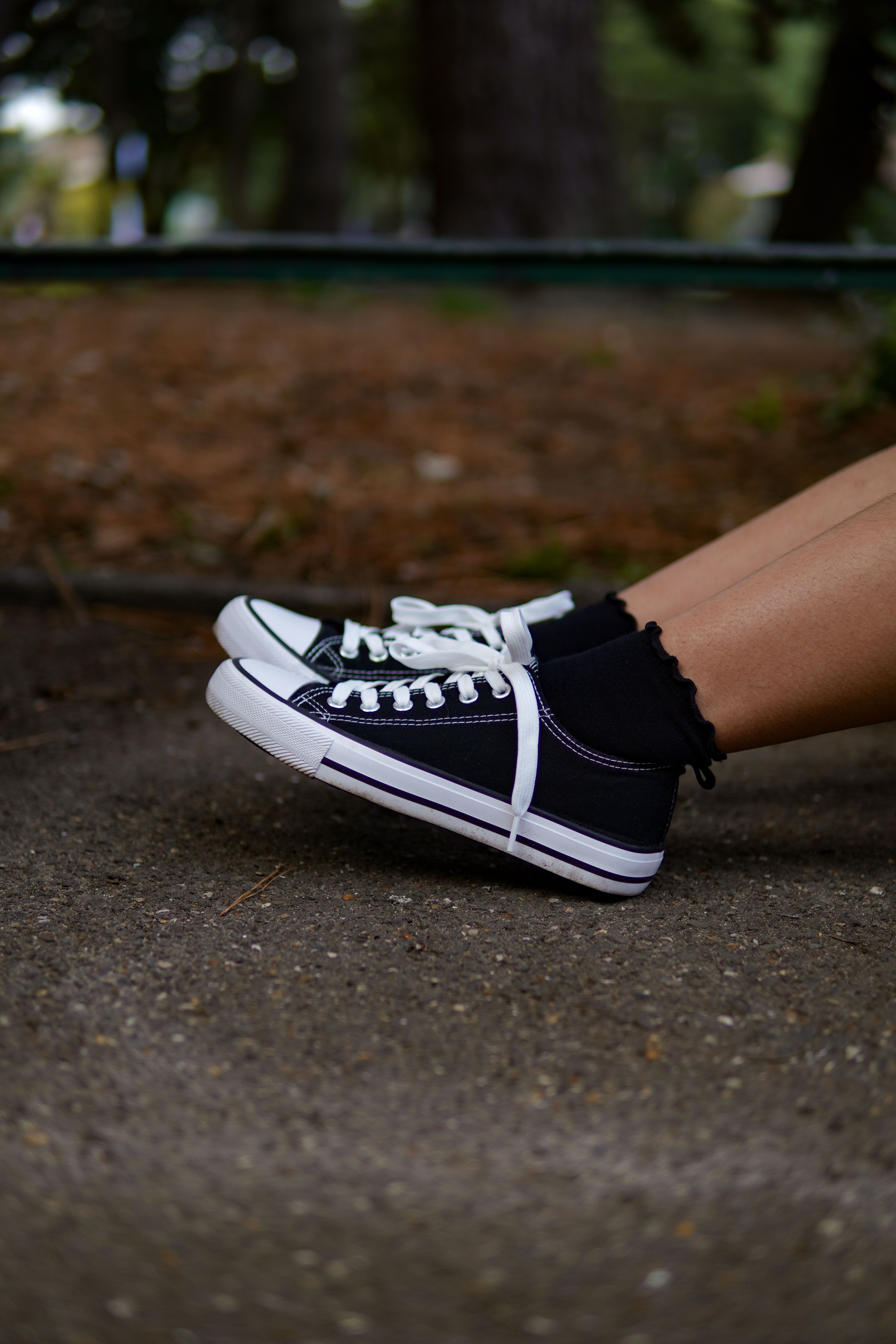 Close-up of black casual sneakers on an outdoor path.