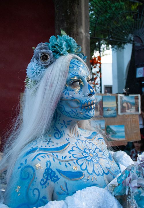Free Stunning Catrina figure with blue makeup and floral headpiece at Día de Muertos celebration. Stock Photo