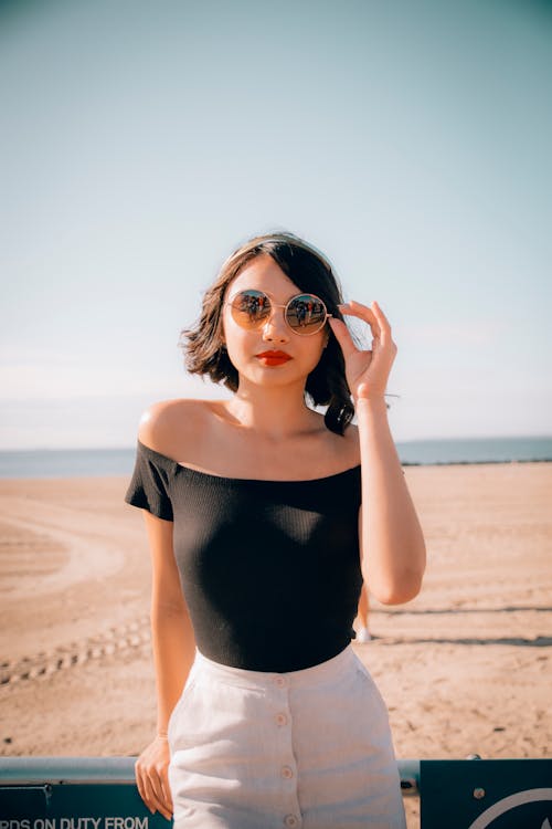 Femme Touchant Ses Lunettes De Soleil En S'appuyant Sur Une Barre De Métal Gris