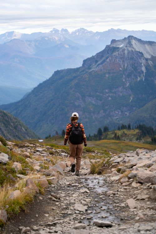 Free A lone hiker explores a rocky trail amidst stunning mountain views in Mount Rainier National Park. Stock Photo