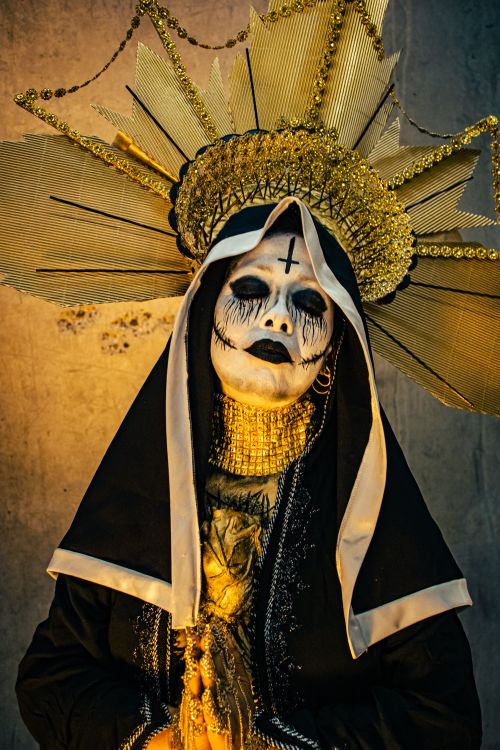Free A striking portrait of a woman in a demonic costume with artistic horror makeup in golden light. Stock Photo