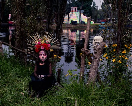 Decorated figure by the riverside celebrating Day of the Dead, vibrant costumes and floral elements.