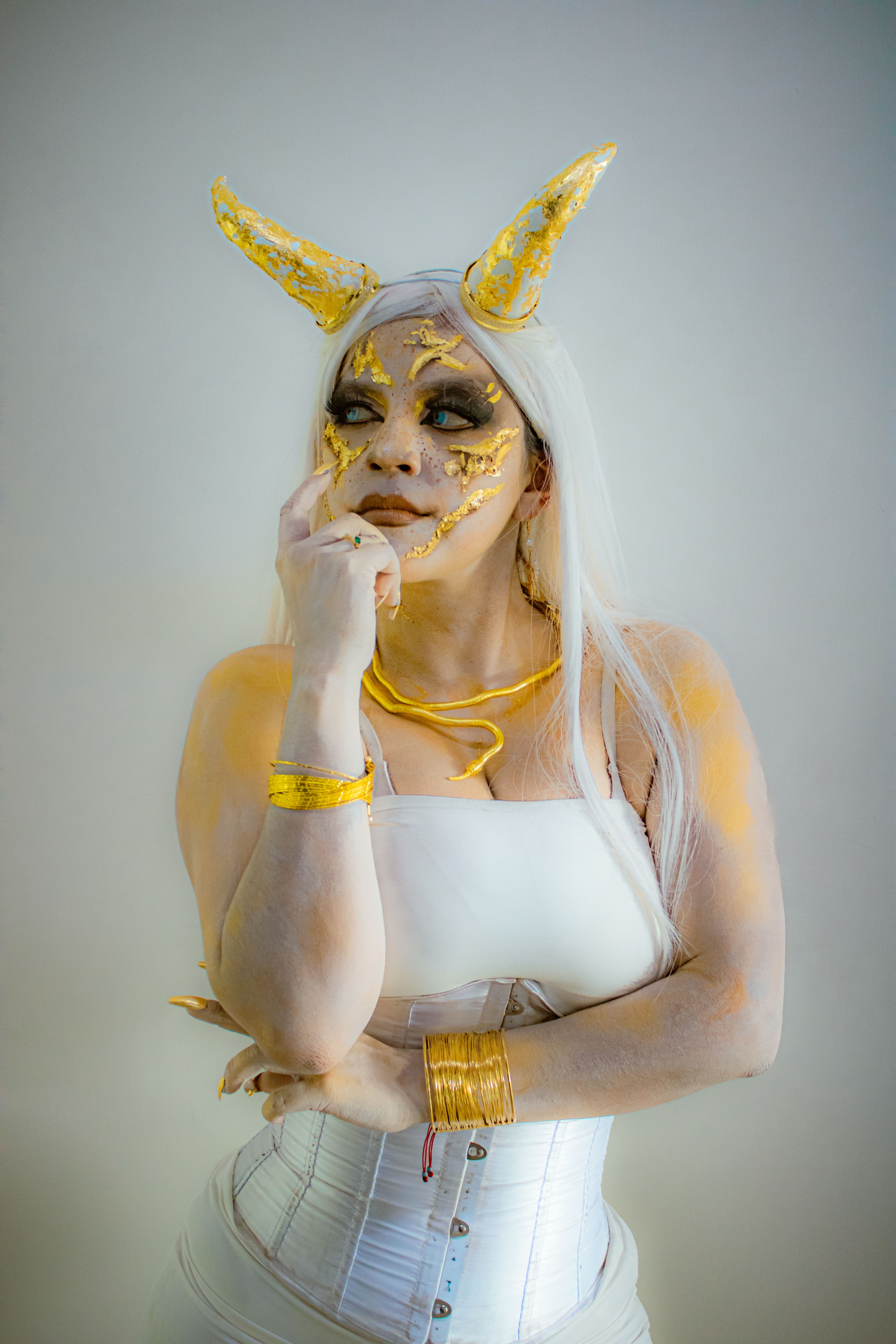 Artistic portrait of a woman in demonic costume with golden horns and makeup.