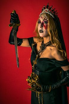 A woman in horror makeup with artistic flair holding a dagger in a dark themed portrait.