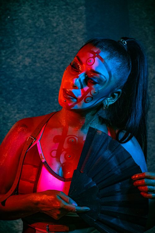 Free A woman with artistic makeup and dual lighting in vibrant red and blue tones. Stock Photo