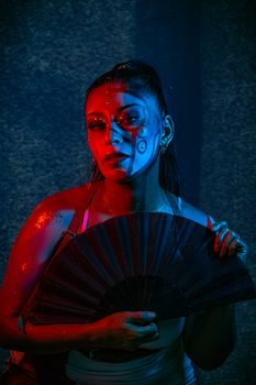 A moody portrait of a woman with artistic horror makeup, illuminated by red and blue lighting.