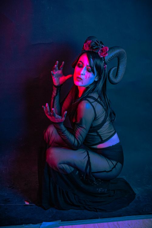 Free Artistic demon-inspired makeup with horns under vivid blue and red lighting. Stock Photo