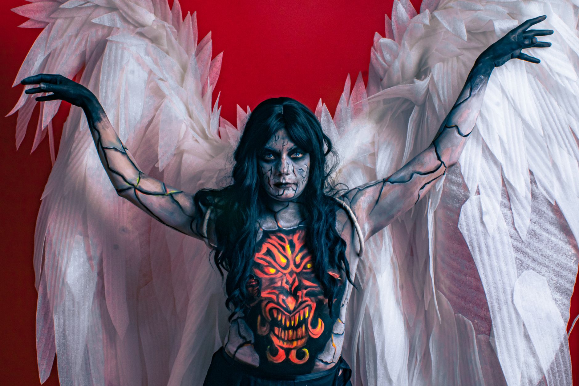 A striking portrayal of an angelic figure with elaborate body paint and wings, evoking horror themes.