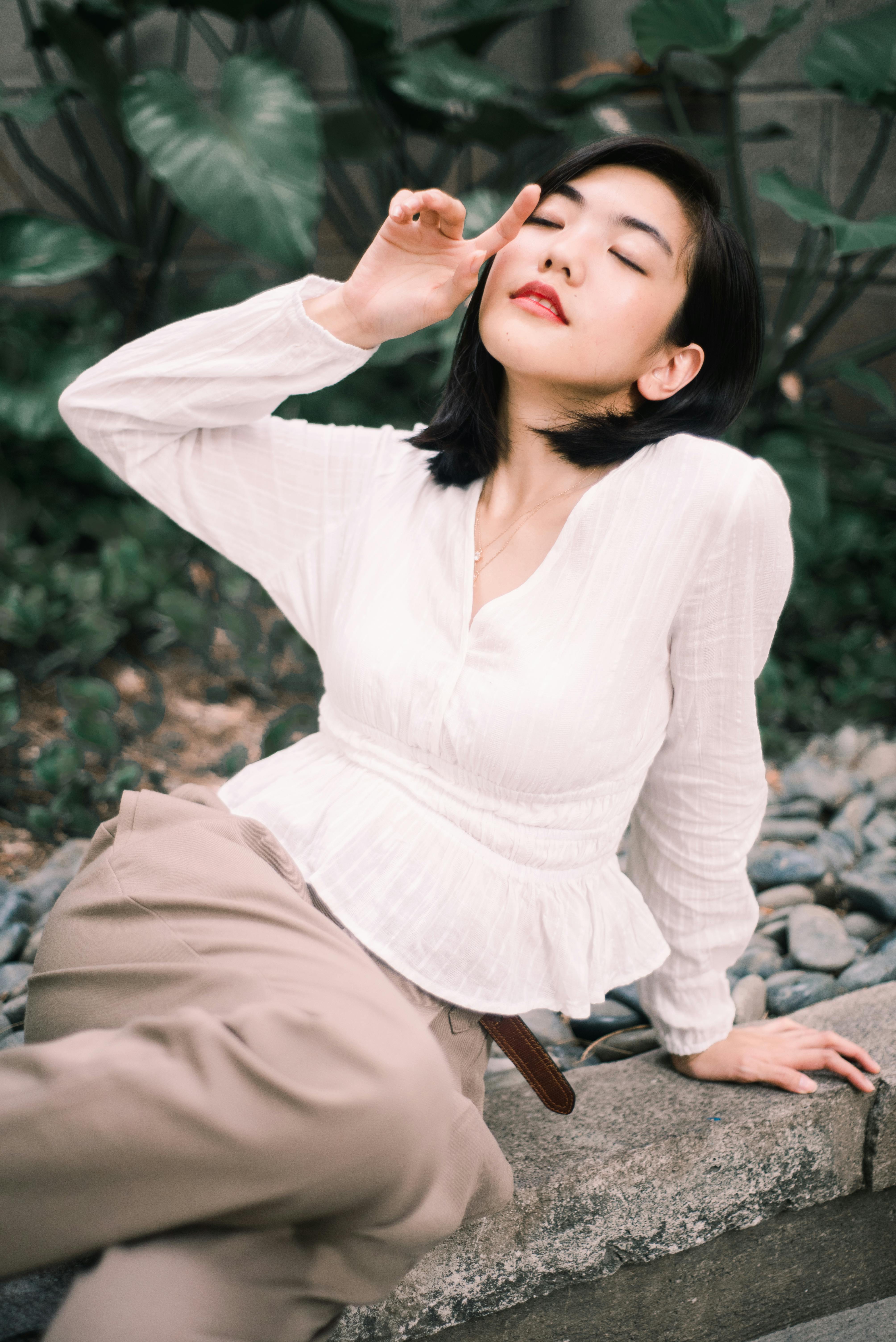 一位年轻女子身着白衬衫，在户外放松身心，这幅宁静的肖像散发着优雅与舒适