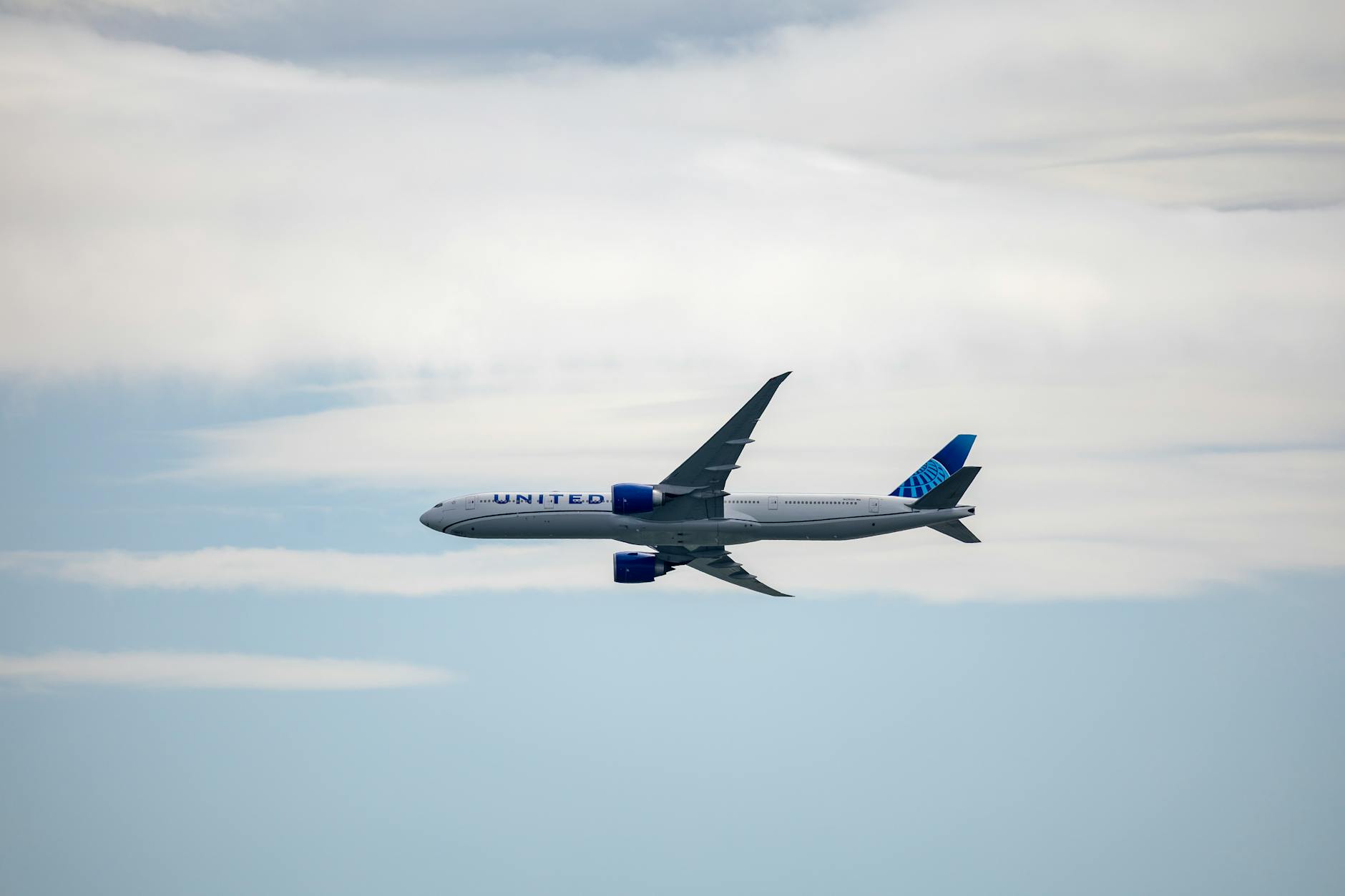 A United airplane soaring in the sky amidst clouds, showcasing modern aviation.