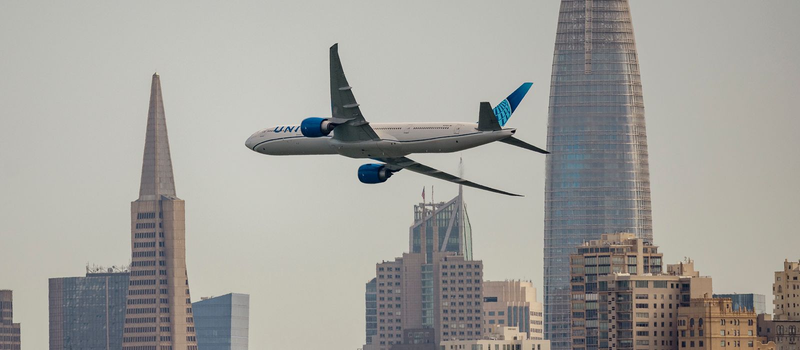 A United Airlines jet soaring over the iconic San Francisco skyline.