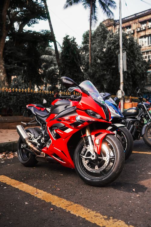 Free A striking red sports motorcycle parked on a city street, capturing urban life and modern transportation. Stock Photo