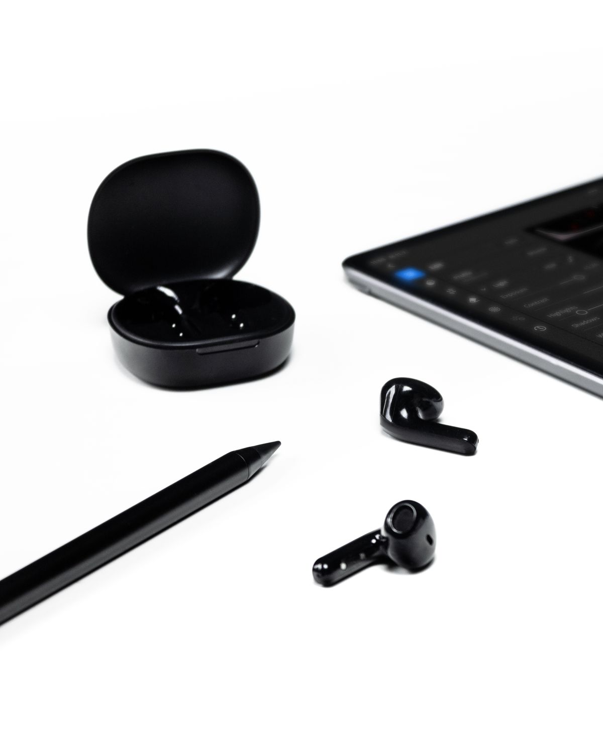 Sleek black wireless earbuds laid out on a clean white surface next to cleaning tools