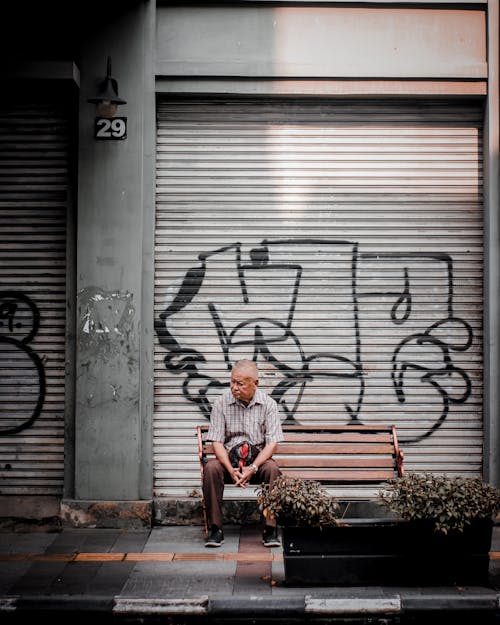 Man Sitting on Bench Beside Metallic Door