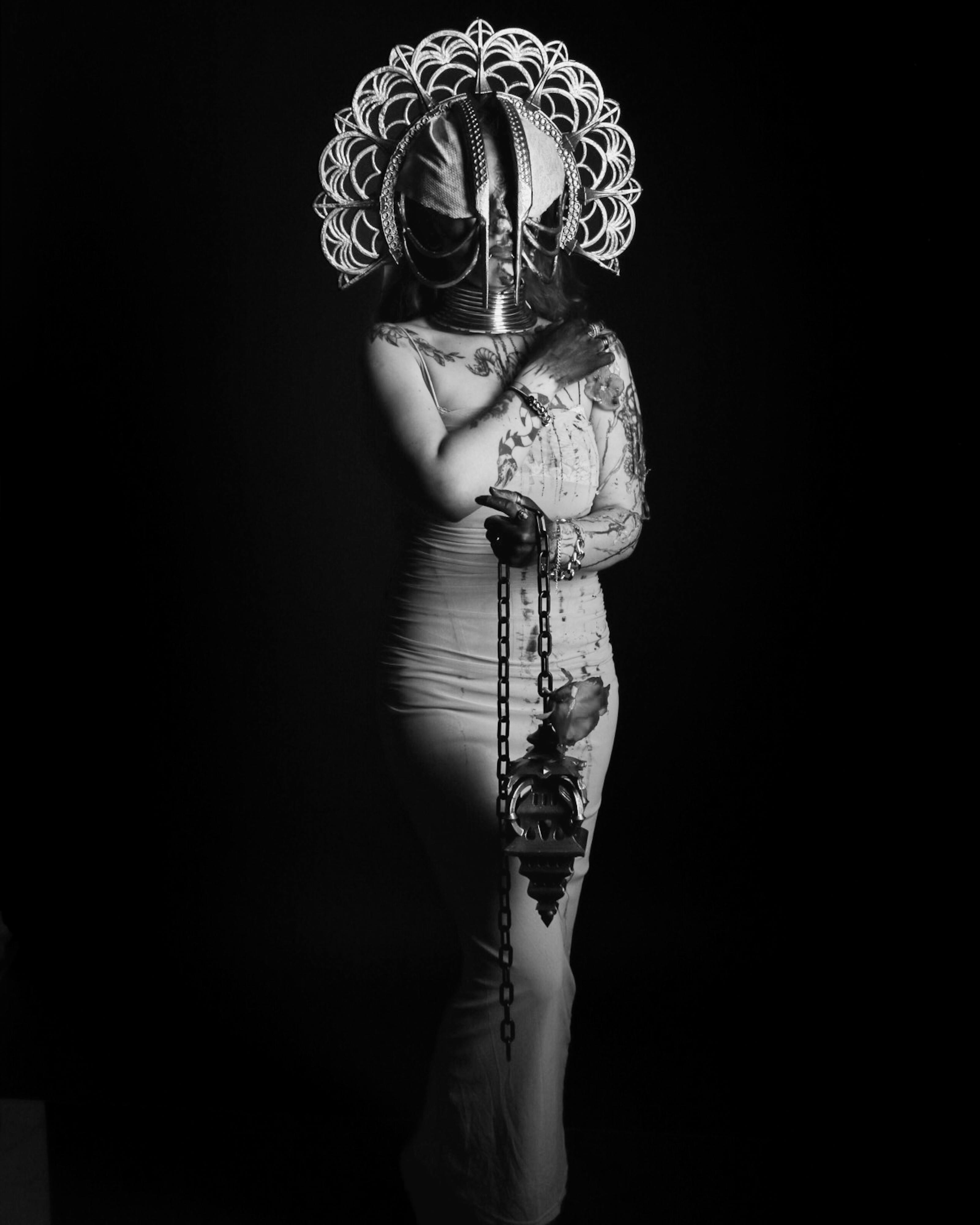 Artistic black and white portrait featuring a person in an ornate headdress under dramatic lighting.
