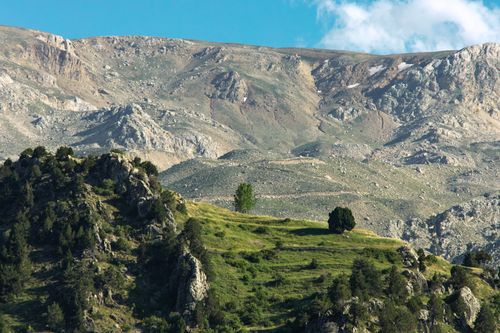 Free A breathtaking mountain landscape showcasing rolling hills, lush greenery, and rugged terrain under a clear blue sky. Stock Photo