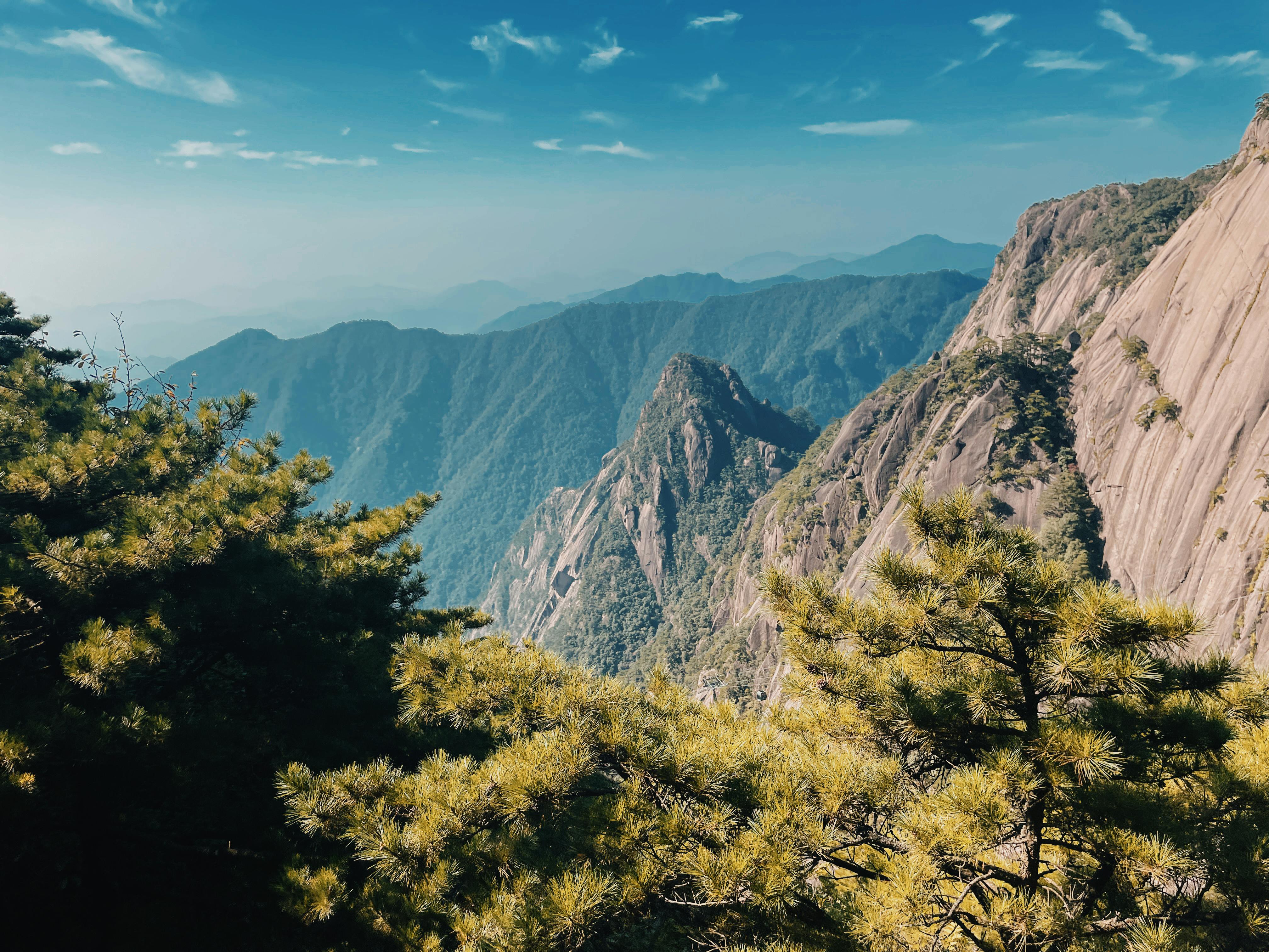 Breathtaking view of the majestic Huangshan mountains with lush green pine trees under a clear sky.
