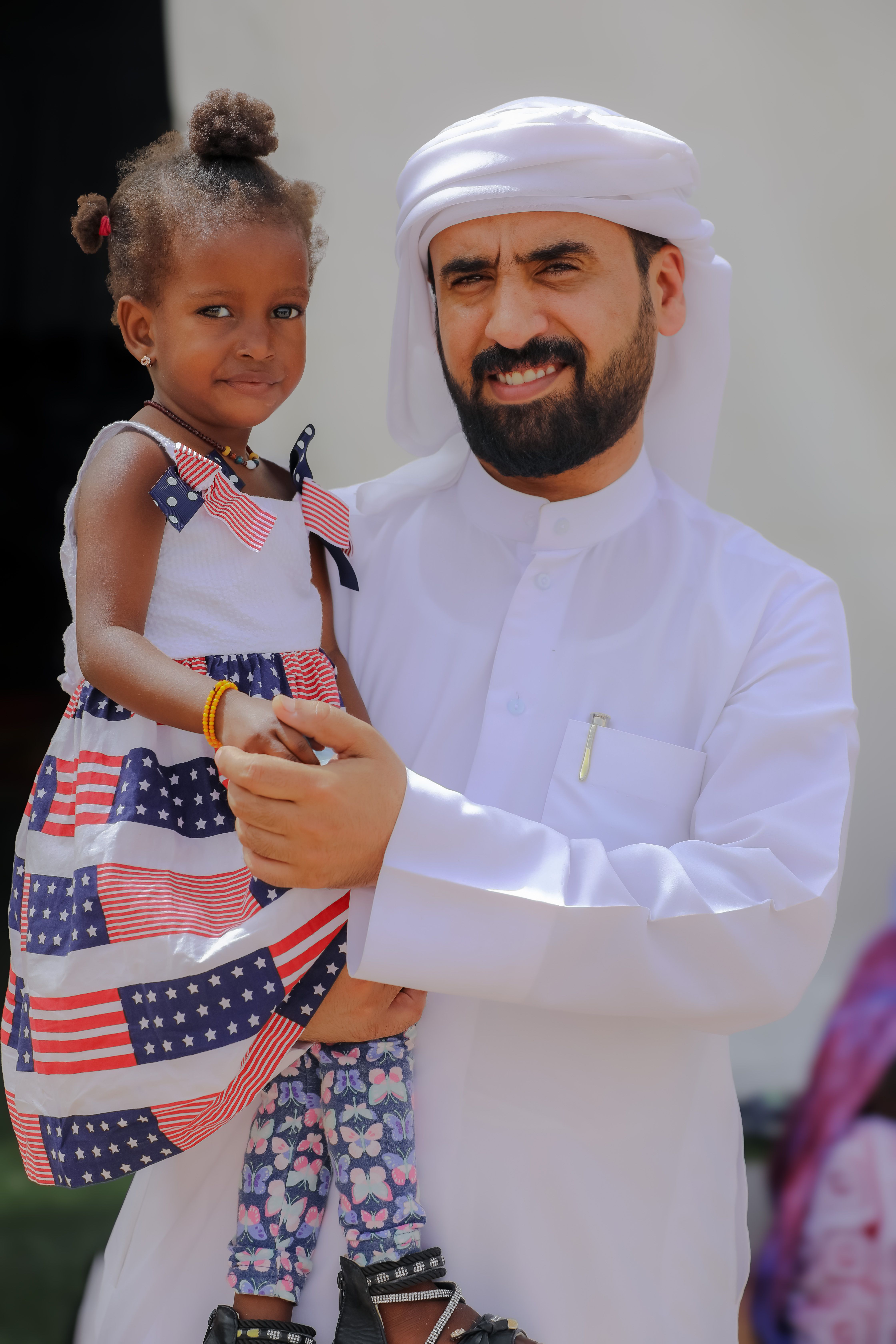 Middle Eastern man holding smiling child outdoors