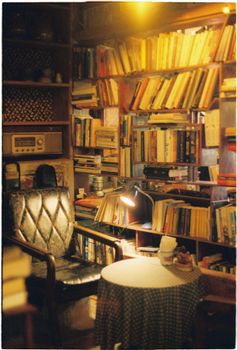 Warm library nook with vintage armchair, books, and ambient lighting.