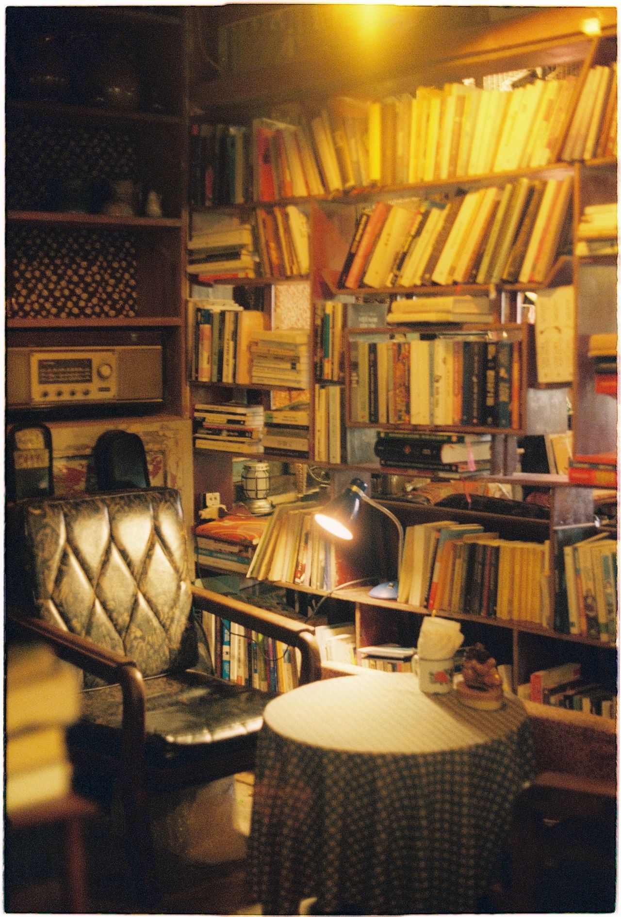 Vintage library corner with leather armchair, books, and a lamp