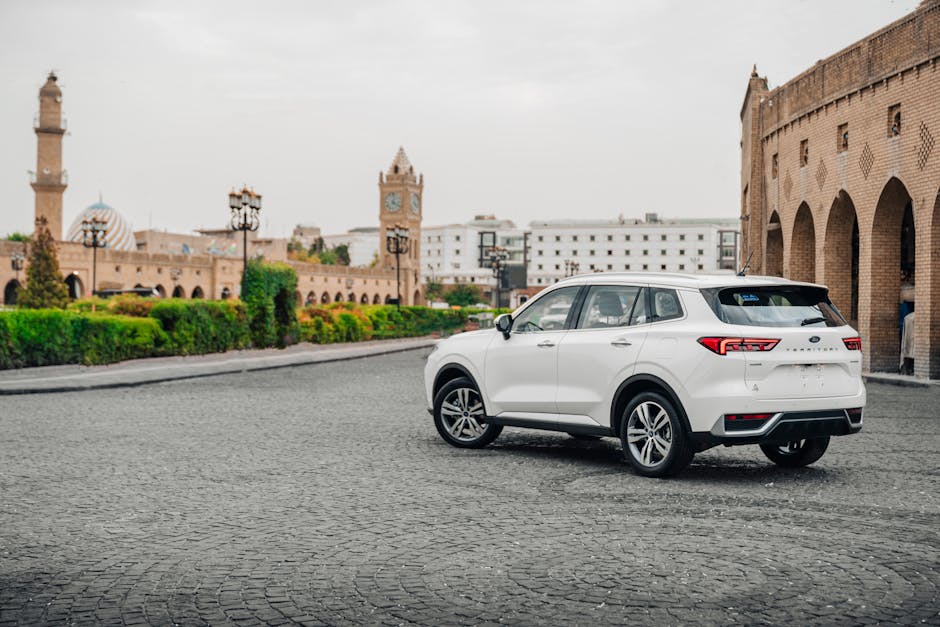 White SUV parked in a historic square in Erbil, Iraq with traditional architecture.