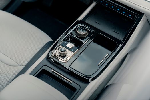 Close-up of a sleek and modern car center console with controls and storage areas.