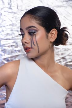 A stylish portrait featuring artistic makeup with a metallic backdrop, showcasing creativity and elegance.