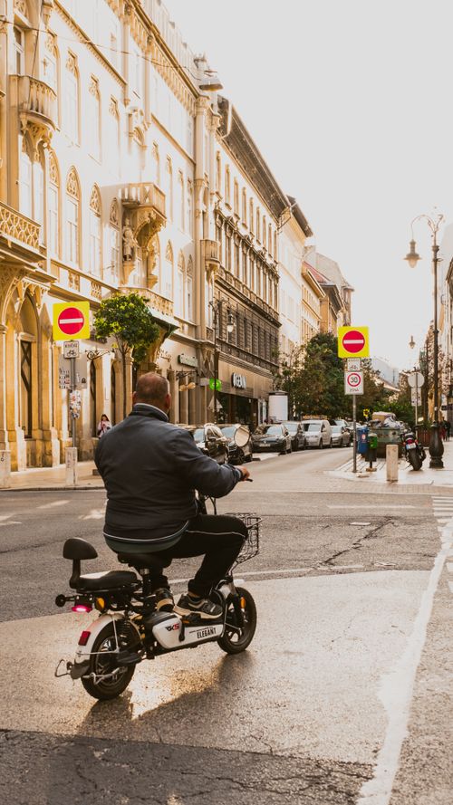 Free Man on a motorcycle rides through a picturesque street in Budapest, Hungary, framed by historic architecture. Stock Photo