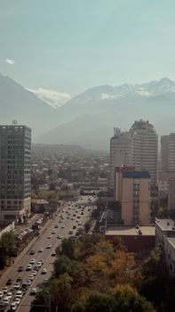 Aerial view of Almaty cityscape with snow-capped mountains in the background.