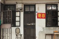 A traditional Chinese building facade with a chair and red signage, capturing urban texture.