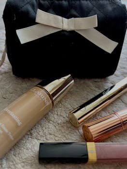 A collection of luxury makeup items with a stylish black cosmetic bag.