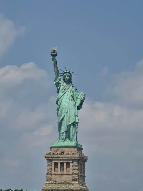 Free Iconic Statue of Liberty against a blue sky in New York City, symbolizing freedom. Stock Photo