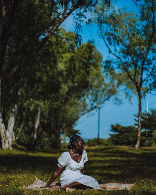 Free A woman enjoying a peaceful picnic in a lush green park with bright blue skies. Stock Photo