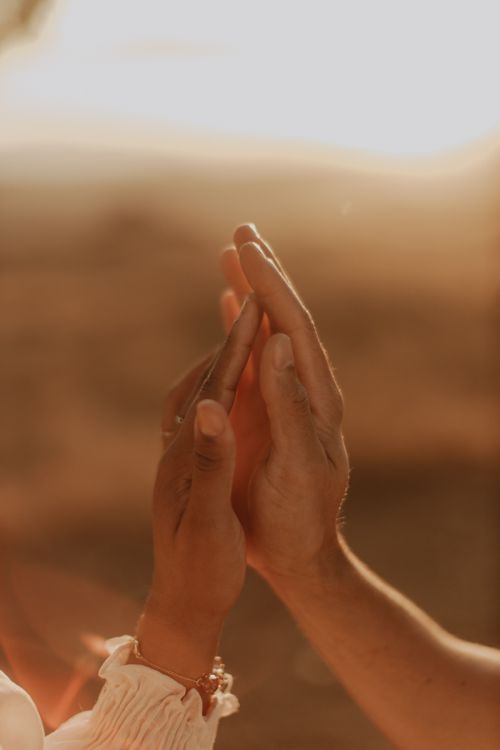 Free Two hands gently touching, with warm golden sunset light, symbolizing unity and connection. Stock Photo