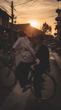 Two people on a bicycle at sunset in a Vietnamese street, creating a serene and warm atmosphere.