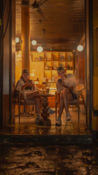 Two friends enjoy a cozy evening at a Vietnamese cafe, engaged in conversation.