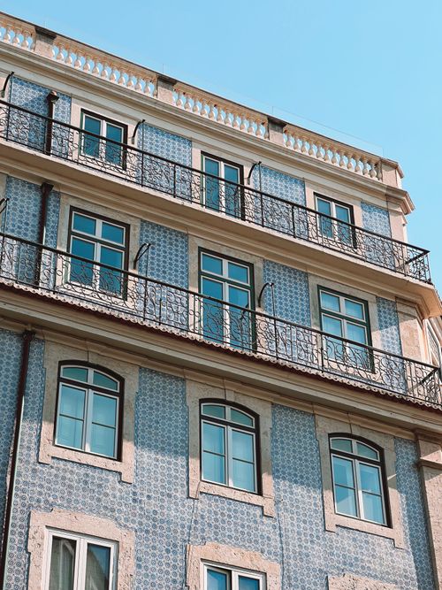 Free Elegant European building facade featuring intricate tile work under a clear blue sky. Stock Photo