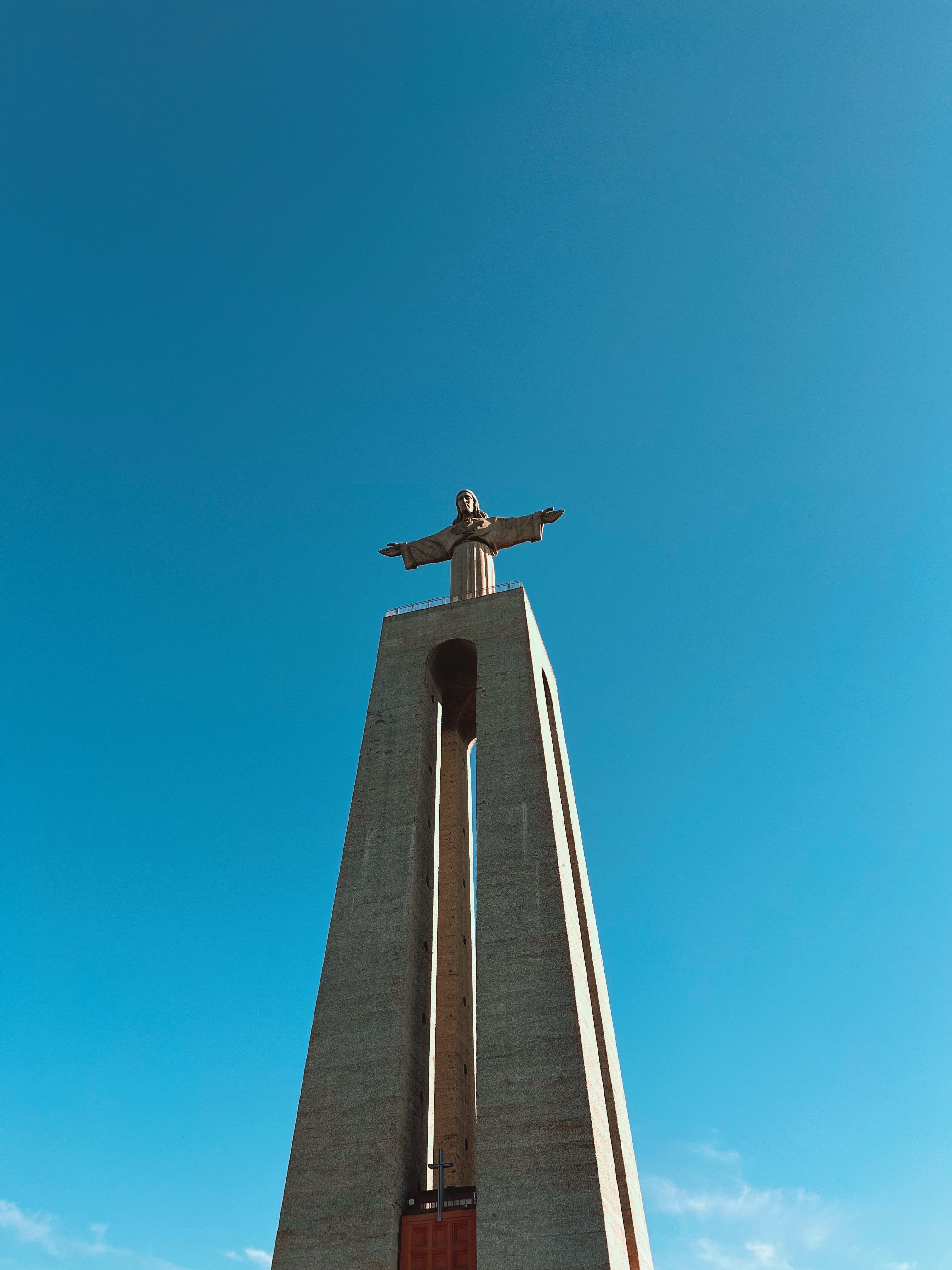 A striking view of the Cristo Rei statue in Lisbon under a clear blue sky.