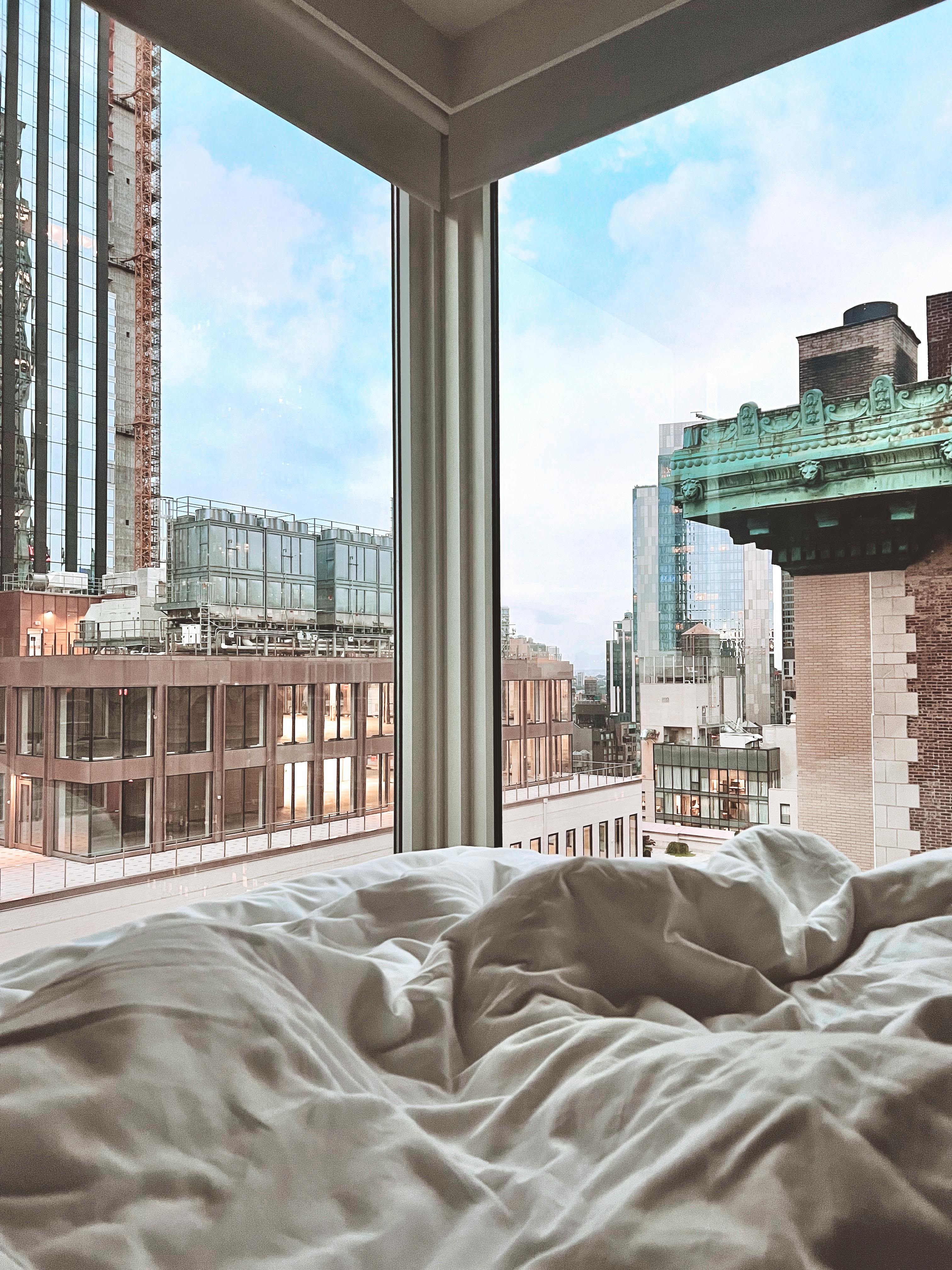 Experience tranquility with a city view from a cozy bed, blending comfort and modern architecture.