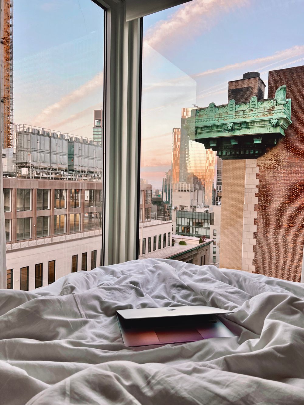 Cama de suite frente a ventanal con vista al skyline de Nueva York al amanecer