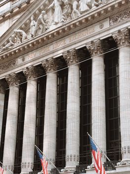 Detailed view of the iconic New York Stock Exchange facade with American flags and columns.