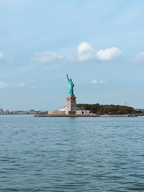 Free The iconic Statue of Liberty on Liberty Island, with a clear blue sky and calm waters. Stock Photo