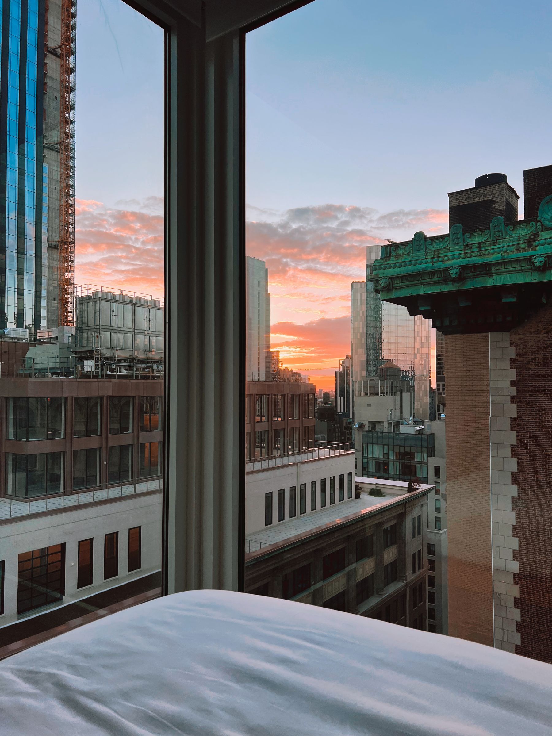 Apartment window overlooking a city skyline at sunset