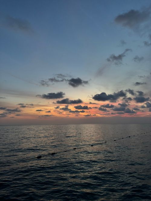 Free A tranquil ocean scene with a vibrant sunset, capturing a serene and calming atmosphere. Stock Photo