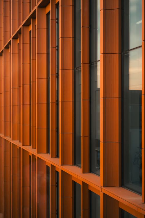 Free A modern building with orange panels in Manchester, UK, reflecting warm sunset tones. Stock Photo