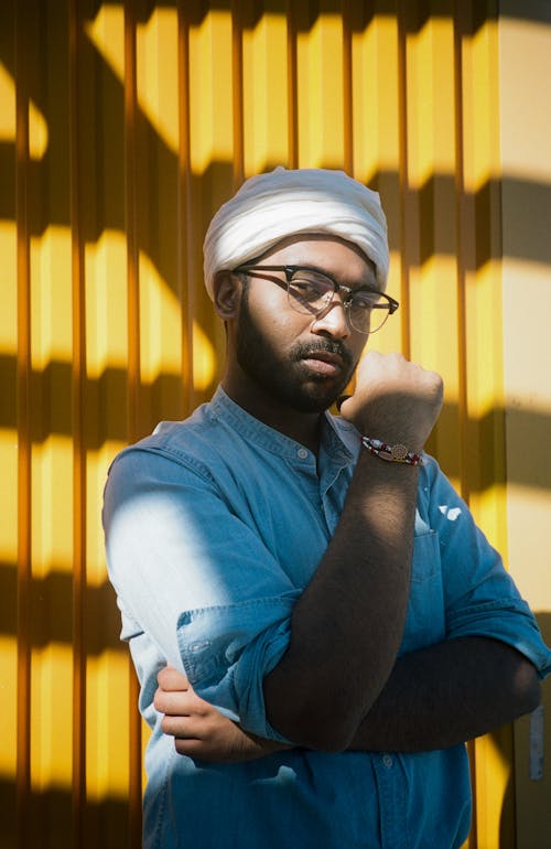 Man Standing Near Yellow Wall Wearing Eyeglasses