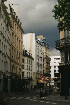 A moody street in Paris with historic buildings and dark clouds overhead, capturing the essence of the city.